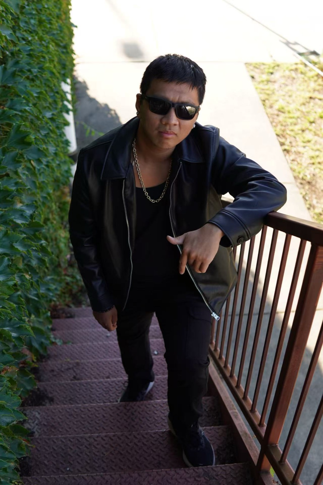 Edward standing on an outdoor staircase in a leather jacket